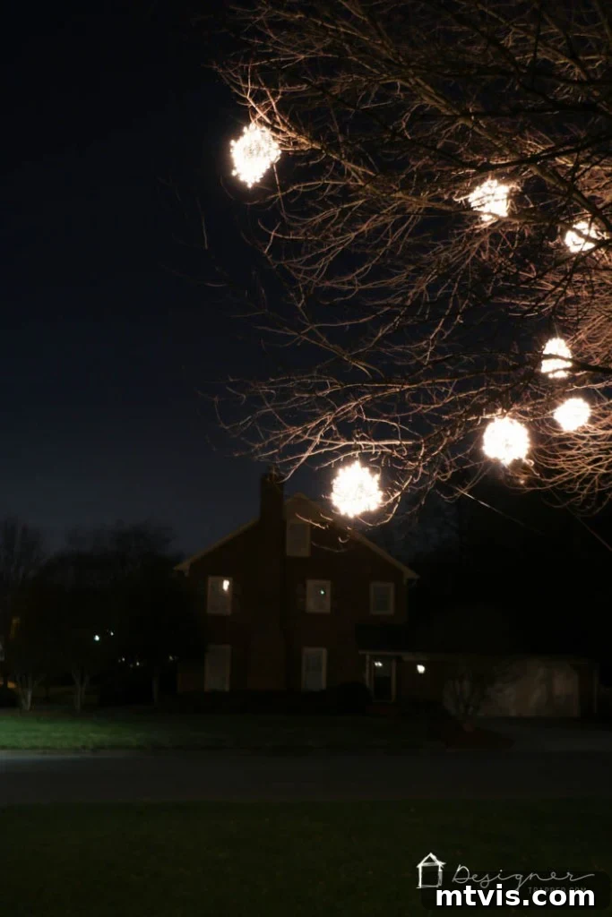 A person admiring the stunning display of white lighted Christmas balls in their front yard.