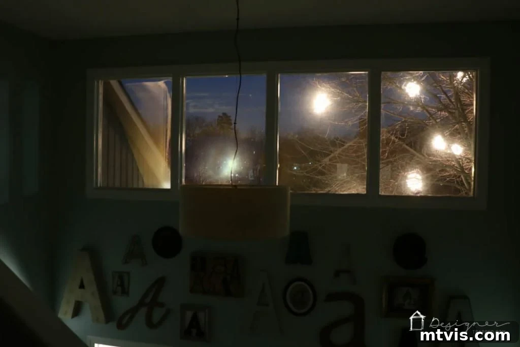 Indoor view from a hallway showing the lighted Christmas balls visible through a window at night.