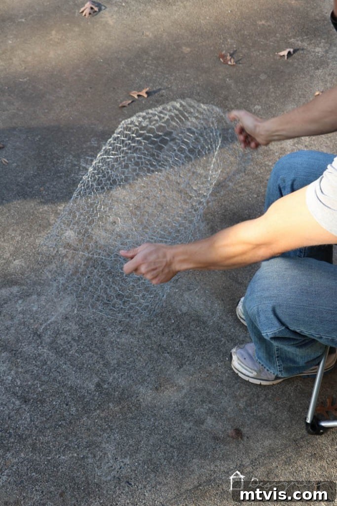 Push and pleat chicken wire tube ends together, twisting wires to sculpt the round Christmas ball shape.