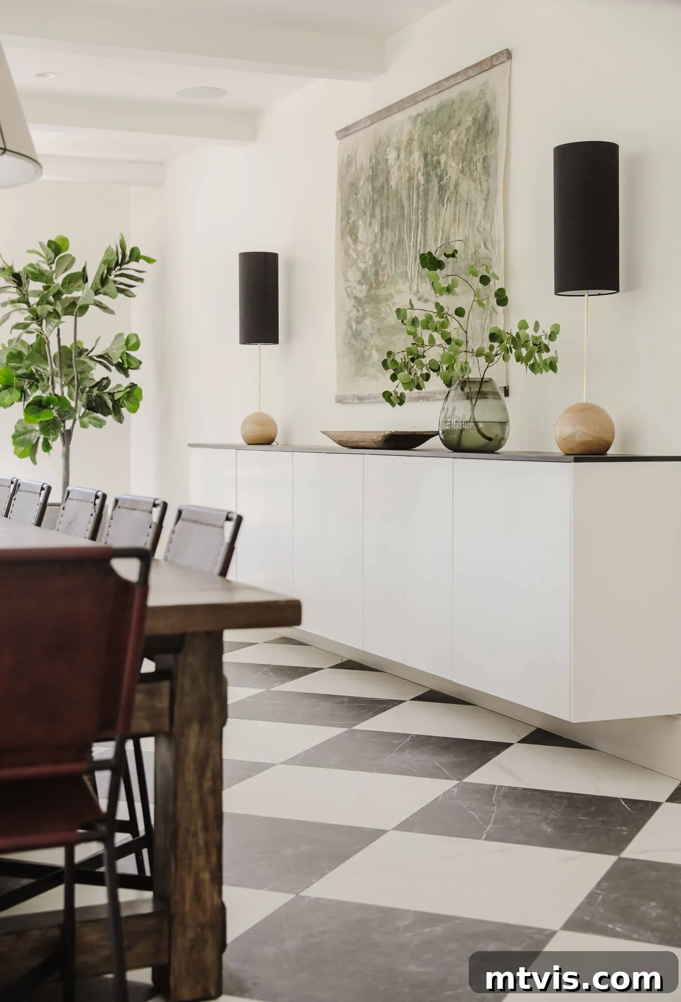50 IKEA Hacks You Won't Believe Are IKEA 18 A minimalist dining room featuring upper IKEA kitchen cabinets ingeniously repurposed as a floating buffet and decorative shelf. A dark dining room table and lush deep green plants enhance the beauty of this stark yet sophisticated space, creating a harmonious balance.