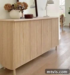 50 IKEA Hacks You Won't Believe Are IKEA 19 A chic hallway console featuring an IKEA Eket sideboard cabinet meticulously covered in decorative pole wrap. The unit is enhanced with added legs and a stylish tabletop, adorned with fresh flowers, a contemporary mirror, and a sophisticated lamp, creating an elegant entryway statement.