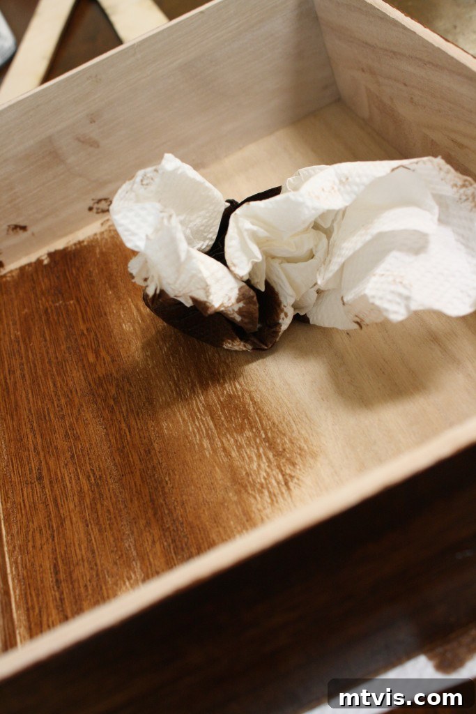 Craft Your Own Desk Organizers 5 Applying wood stain to an unfinished desk organizer tray, showing the rich color transformation during the DIY process.