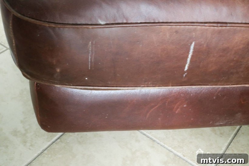 Another view of the damaged leather furniture before restoration, highlighting surface imperfections and wear.