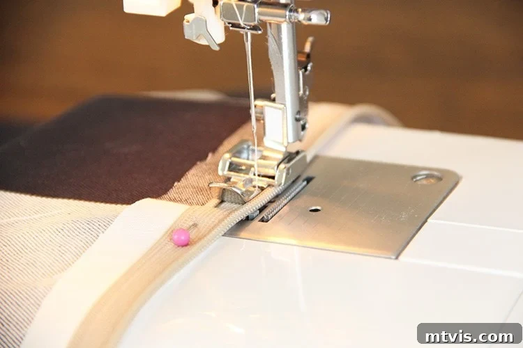 Sewing a Zippered Pillow Cover 9 Sewing machine stitching the first side of a zipper onto fabric, with the zipper foot in action.