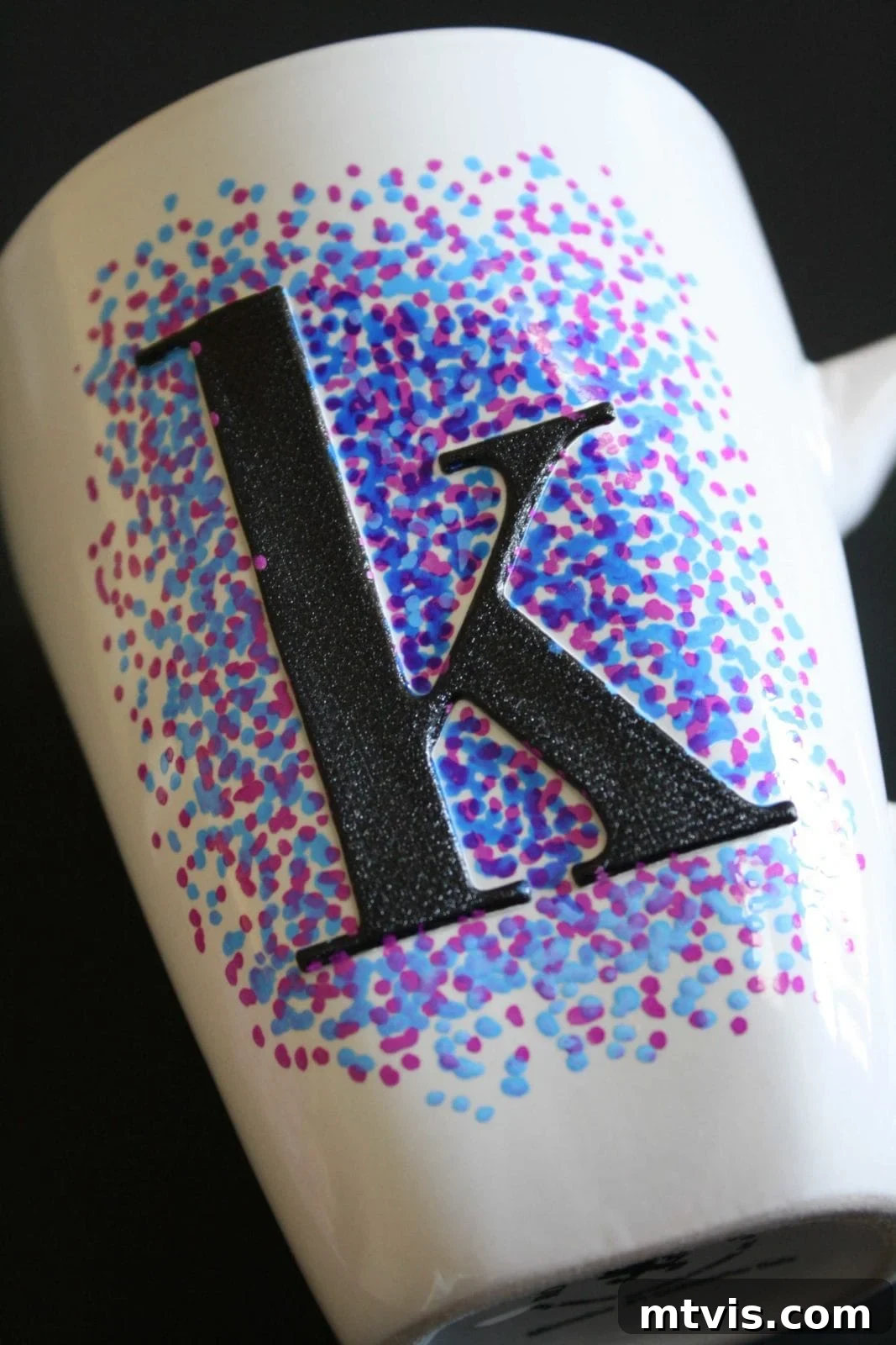 Playful Dotted Sharpie Mugs 4 A white mug with a dimensional "K" craft sticker is surrounded by dots made with oil-based Sharpie markers in blues and purples. Dotted Sharpie mugs are an easy and fun craft for all ages.
