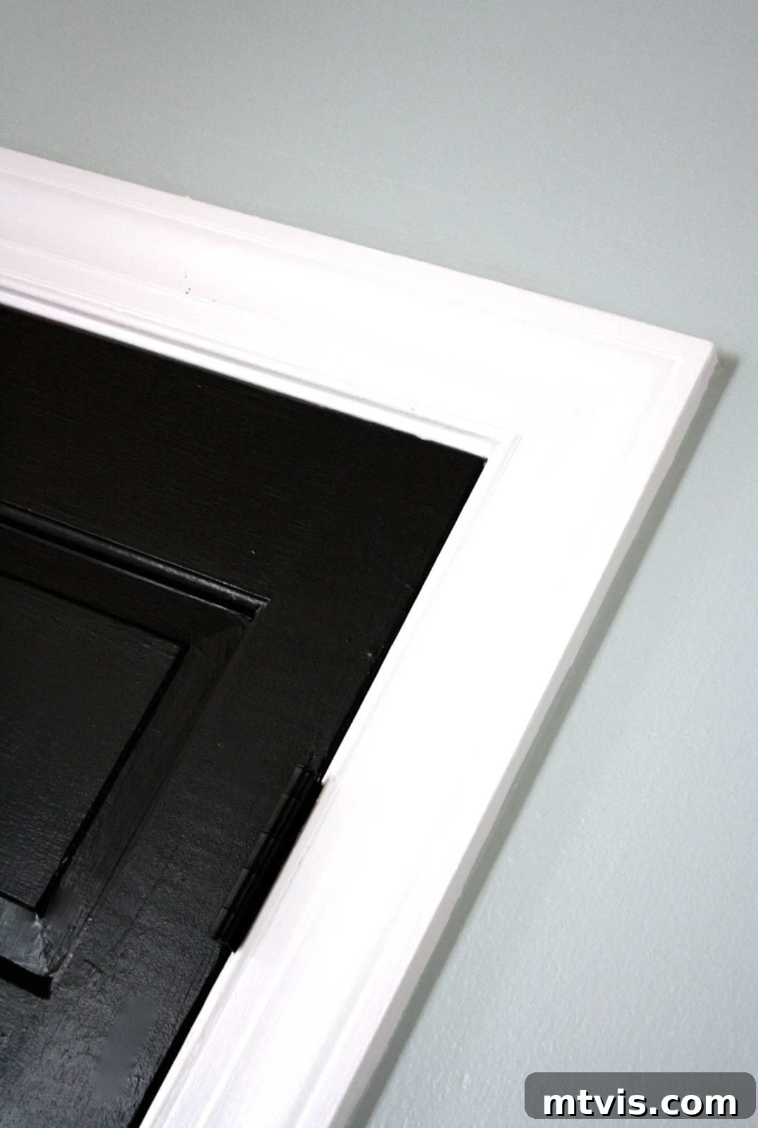 DIY Drama Black Doors White Trim 5 A close-up of the corner of the pantry door trim which has been painted a shockingly bright white, which compliments the black doors.