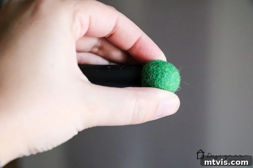 Adding green felt balls to the dowel ends for decoration