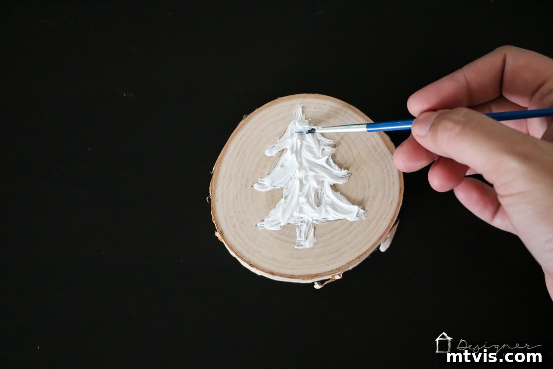Create Stunning Textured Holiday Decor 6 Using a paintbrush to spread and texture the caulk within the Christmas tree outline on the wood slice.