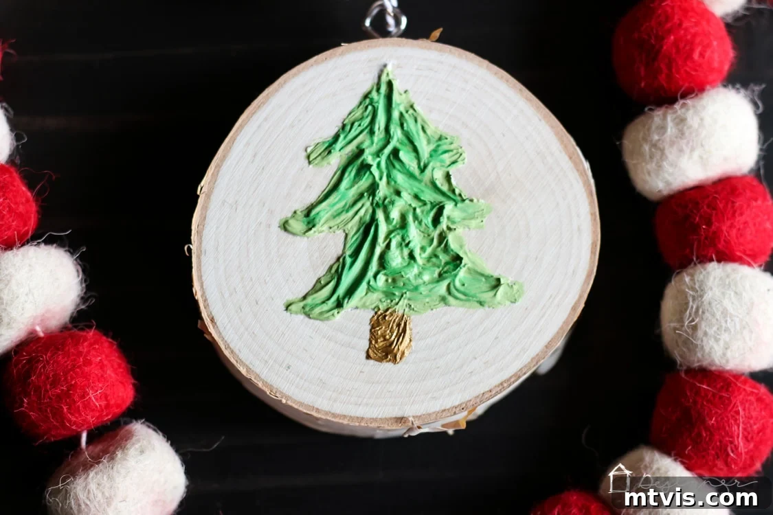 Create Stunning Textured Holiday Decor 10 The final textured Christmas tree ornament on a wood slice, ready to be hung, showcasing intricate caulk texture.