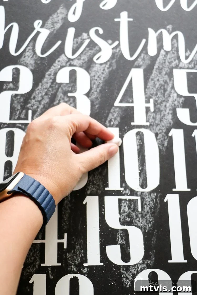 Handcrafted Christmas Countdown 9 Hand applying chalk to a board with vinyl lettering, creating a faux chalkboard art effect.