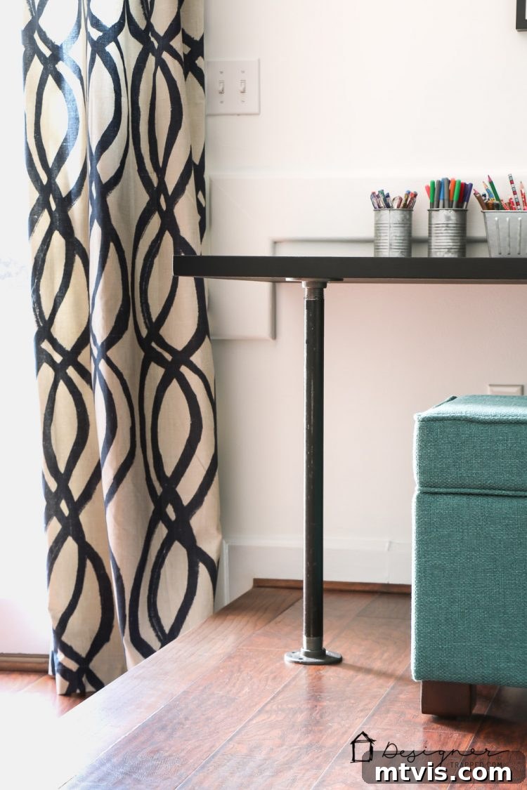 Detailed view of the industrial black pipe legs on the DIY desk, emphasizing the rugged aesthetic and sturdy construction.