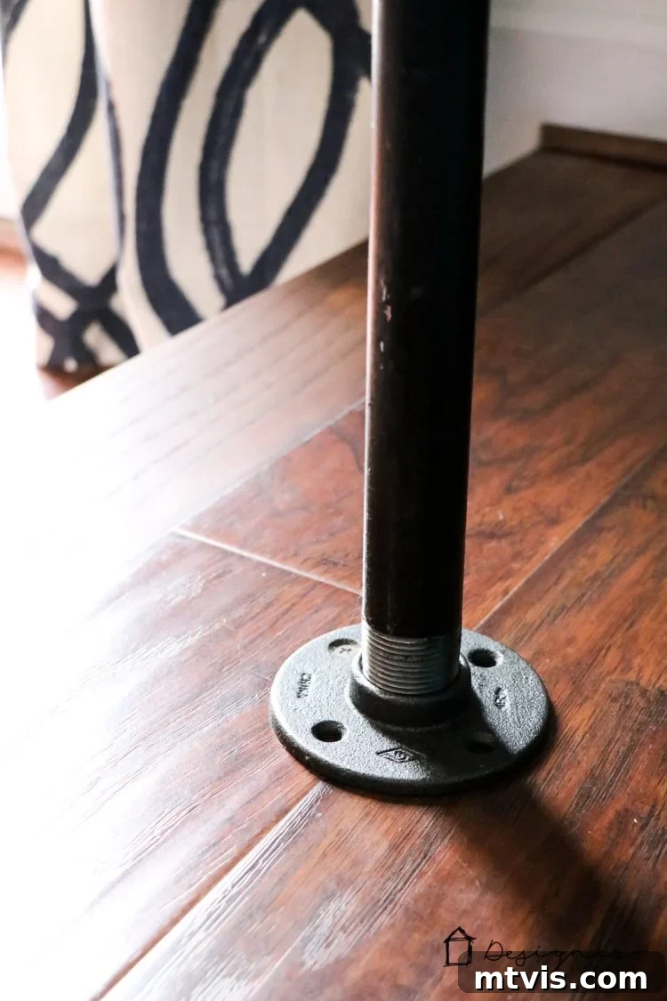 Detail of a floor flange securely fastened to the floor with a screw, enhancing the stability of the DIY pipe desk.