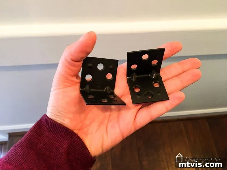 Attaching a black right angle bracket to the wall for securing a DIY pipe desk, ensuring stability.