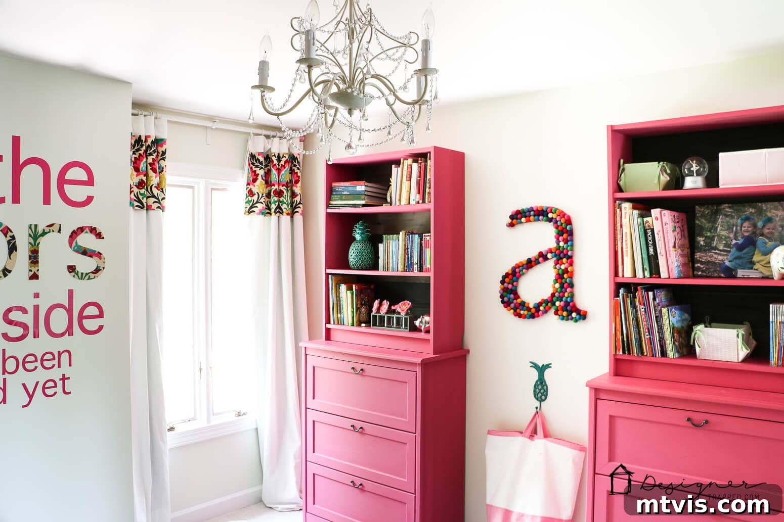 Billy Bookcase Brilliance: IKEA Hacks for Ultimate Storage 11 A charming girl's room featuring pink bookcases neatly stacked on dressers along one wall, complemented by a sparkling chandelier and a decorative felt-ball letter 'A.'