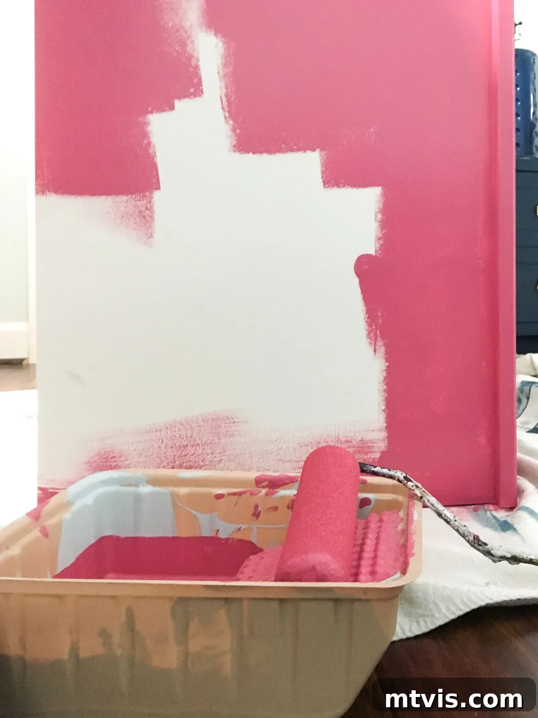 Image showing a piece of IKEA laminate furniture being carefully painted pink with a foam roller