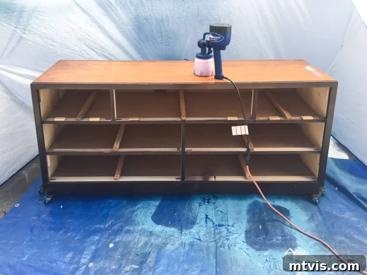 Transform Your Furniture: The DIY Restoration Guide 6 HomeRight sprayer being used to apply paint to a dresser in a spray shelter.