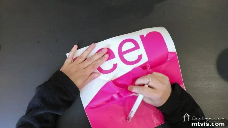 Process of 'weeding' a vinyl decal, carefully removing excess vinyl from around the cut letters to reveal the final design.