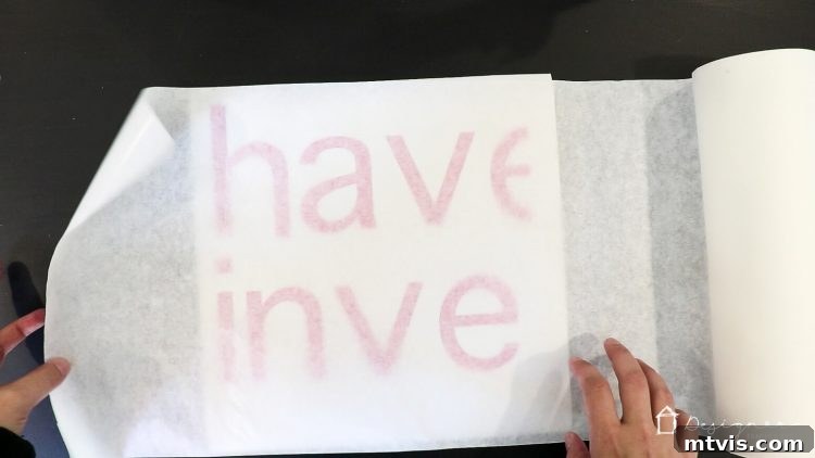 Applying transfer tape over weeded vinyl letters and using a scraper tool to ensure adhesion, preparing the decal for wall application.