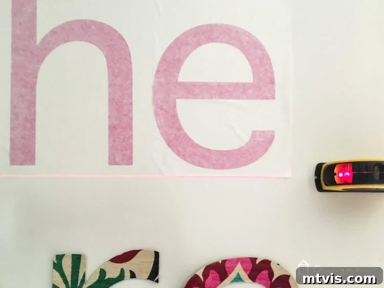 Applying vinyl wall decals to the wall using transfer tape and a scraper, ensuring a level and smooth application.