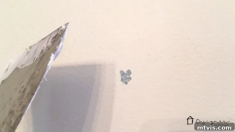 Detail shot of wall after old vinyl decal removal, showing small areas of paint damage that require patching for a smooth surface.