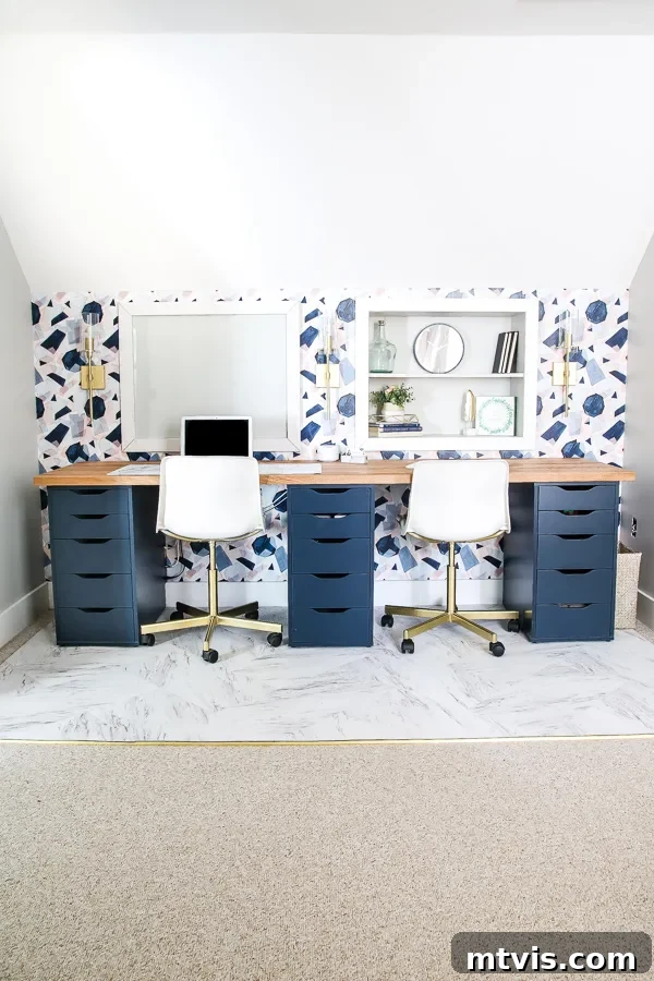 Smart IKEA Desk Upgrades on a Budget 15 An elegant IKEA desk hack features rich navy drawers, a natural wood countertop, and seamlessly integrated shelves against a wall adorned with blue-patterned wallpaper, all nestled beneath an inviting attic roof slope.