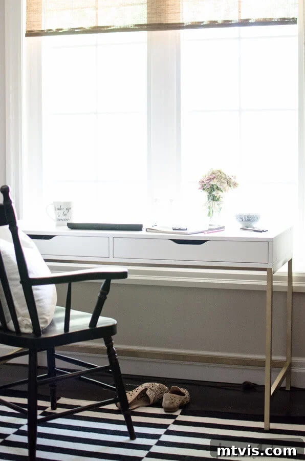 Smart IKEA Desk Upgrades on a Budget 7 A slim white desk with two under-mounted drawers provides a work area that takes up little space. A wooden black chair and slippers on a black and white rug complete this IKEA desk hack.