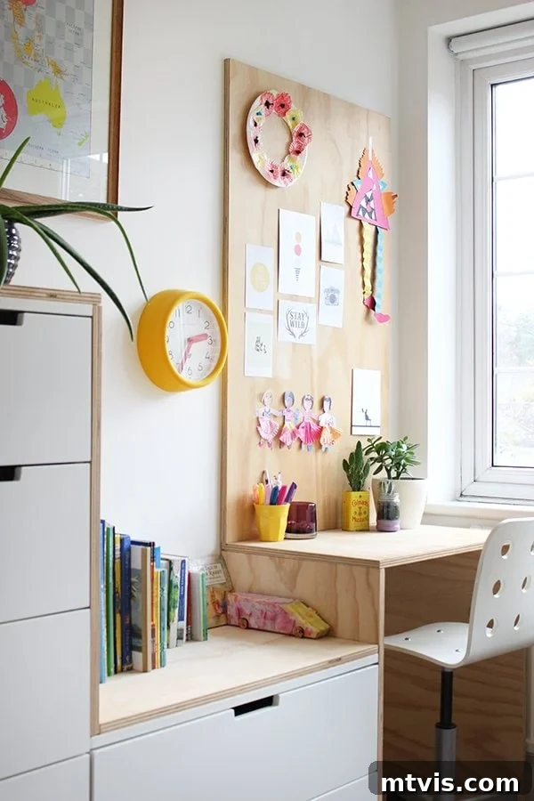 Smart IKEA Desk Upgrades on a Budget 8 A compact plywood desk with a display of children's artwork on the wall, beside sizable IKEA storage bins that contain children's books and various supplies for a playroom. IKEA desk hacks can be for kids and adults.