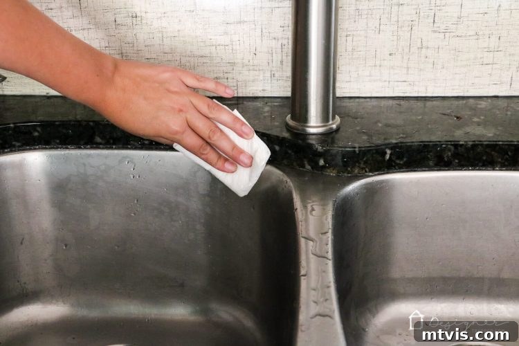 A hand cleaning the newly scraped caulk joint with a paper towel dampened with rubbing alcohol. Preparing surface for new caulk.
