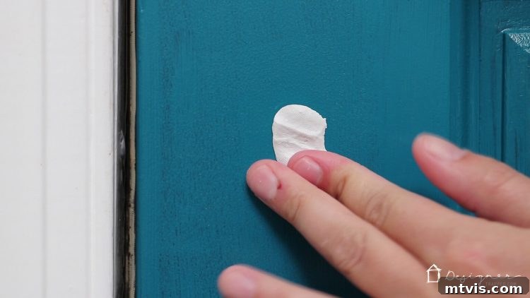 Make Door Holes Vanish: Your DIY Guide 4 Hands carefully applying epoxy putty to a damaged door, ensuring complete coverage and a smooth surface for DIY repair.
