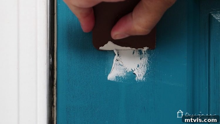 Make Door Holes Vanish: Your DIY Guide 5 A credit card being used to expertly level and smooth freshly applied epoxy putty on a door, creating a flush repair.
