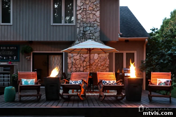 A wide view of the illuminated DIY deck at night, showcasing the magical glow of the fire columns and the inviting atmosphere of the outdoor living space.