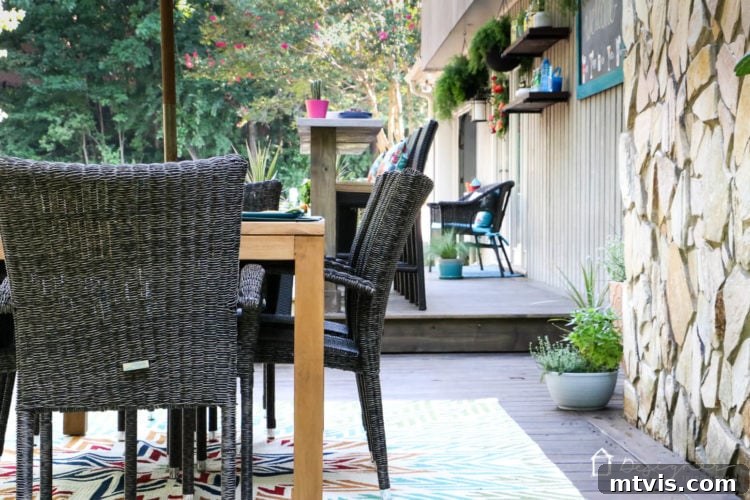 Detail shot of the new deck’s dining area, featuring a teak table and wicker chairs, highlighting the blend of natural and all-weather materials.