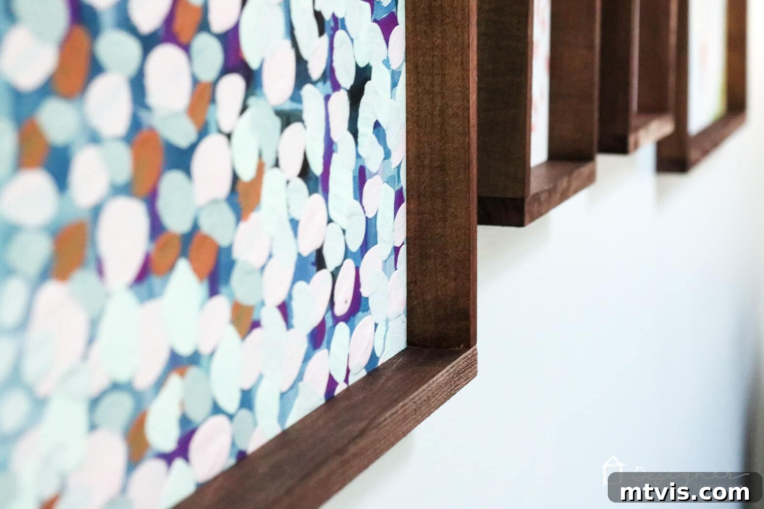 Build Custom Frames for Your Oversized Art 12 A close-up view of the bottom right corners of several DIY picture frames, showcasing their deep brown stain and clean lines, hanging artfully on a wall at an inviting angle.