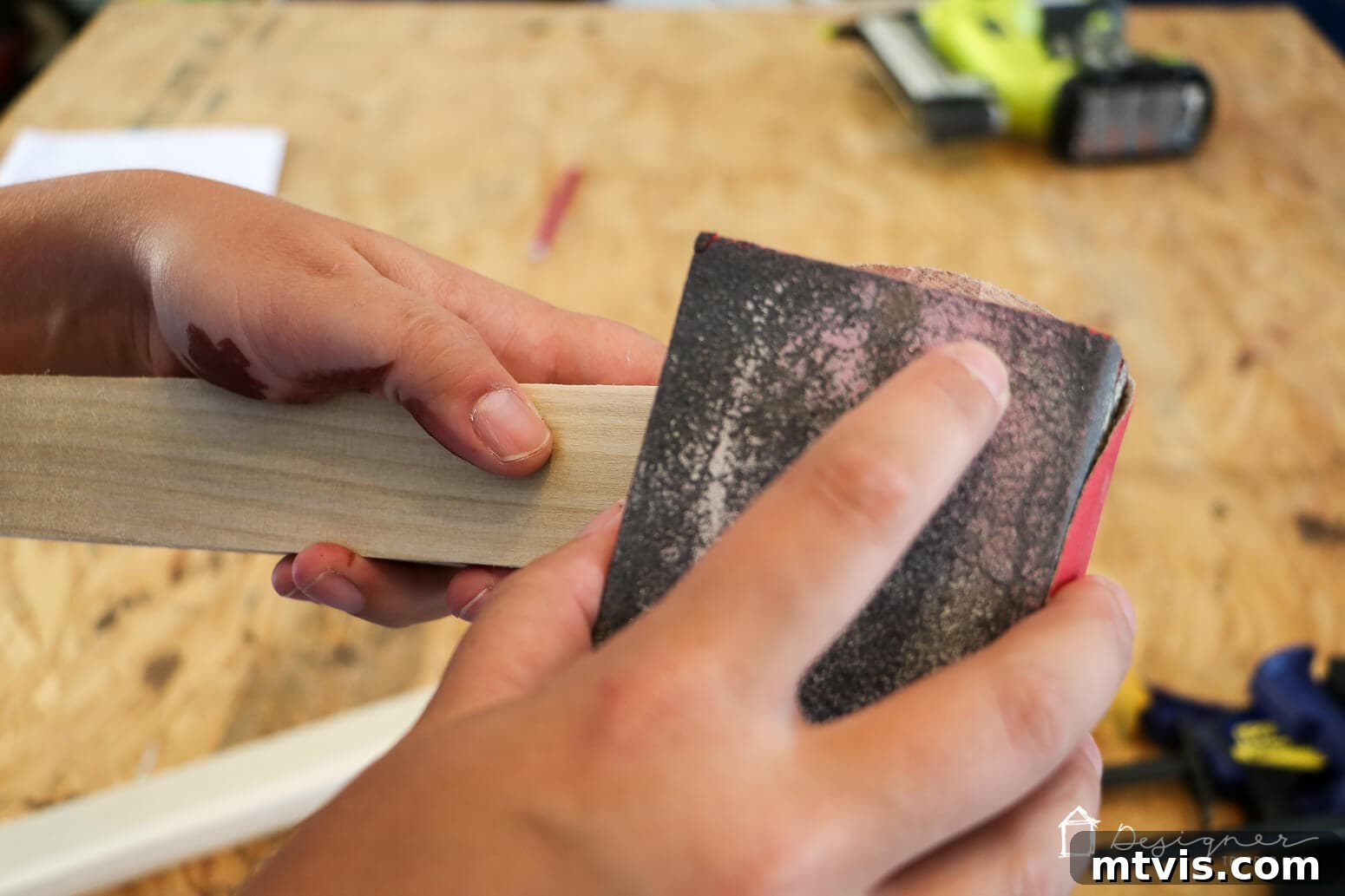 Build Custom Frames for Your Oversized Art 5 A close-up shot of Tasha's hand meticulously sanding a section of a wooden frame with a sanding block, an important step in her tutorial on how to make a picture frame for a smooth finish.
