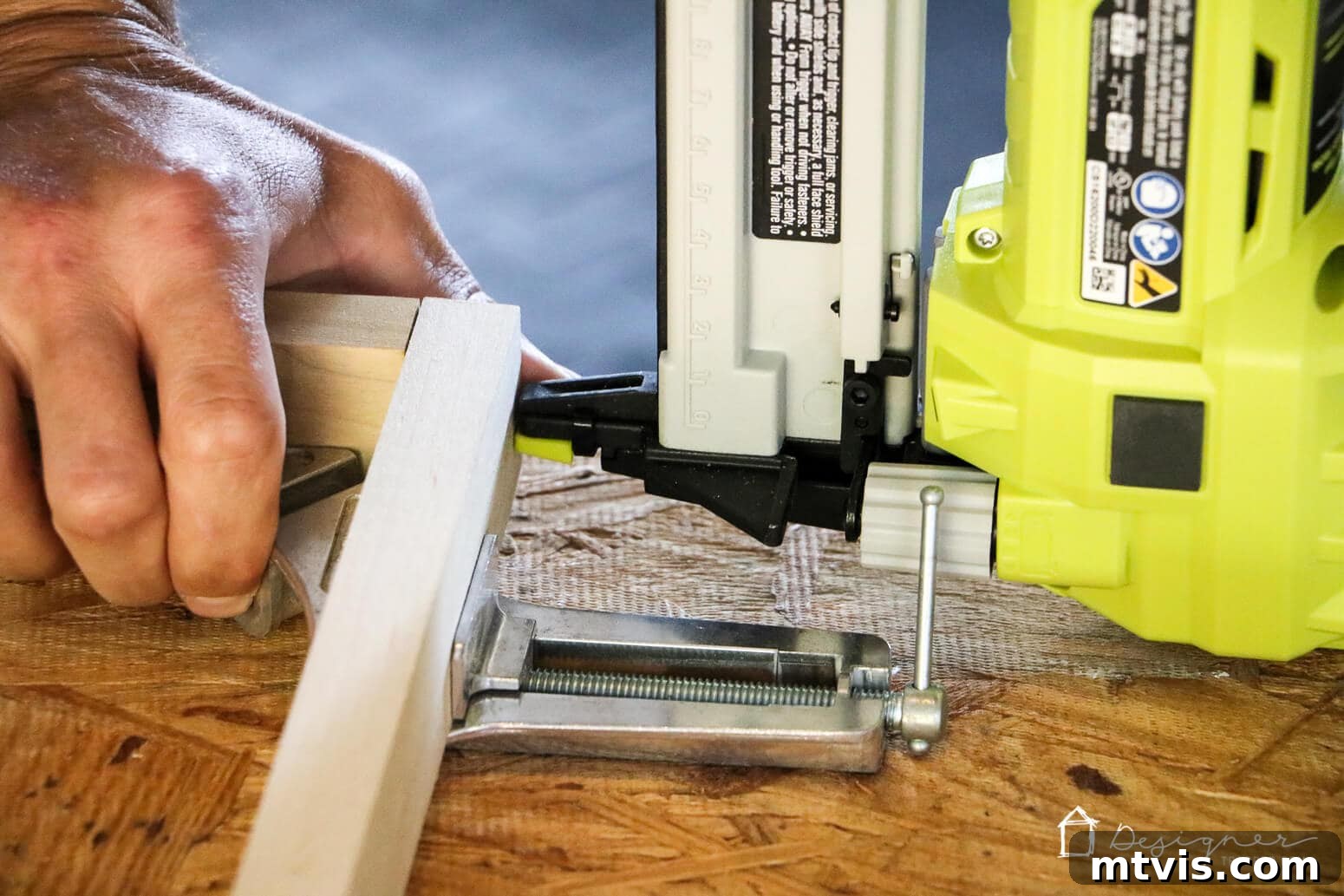 Build Custom Frames for Your Oversized Art 6 A detailed close-up shows a person skillfully using a nail gun to securely join two pieces of wood at a perfect right angle, demonstrating the frame assembly process for DIY large art frames.