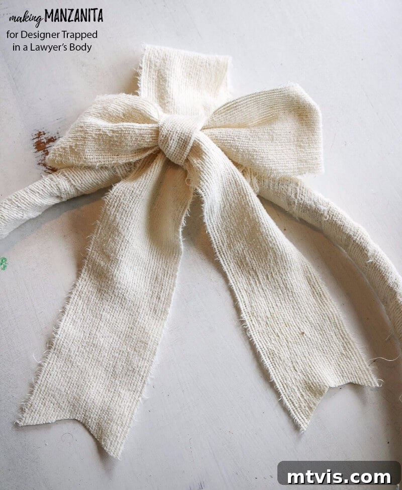 Craft Your Boho Winter Wreath 10 Complete your DIY Boho Winter Wreath by adding a fabric hanger and a simple fabric bow at the top. Secure both with hot glue for a finished, cohesive look that's ready for display.