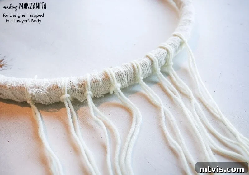 Craft Your Boho Winter Wreath 5 Attach white and tan yarn, along with ripped fabric strips, to the bottom of your DIY Boho Winter Wreath. Vary the lengths and add braids to create rich texture and a flowing, bohemian aesthetic.