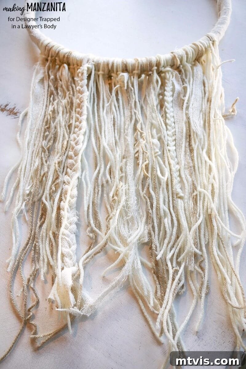 Craft Your Boho Winter Wreath 6 Close-up view of the textured yarn and fabric strands on the DIY Boho Winter Wreath, showcasing the varied lengths, soft colors, and intricate details that create its charming bohemian appeal.