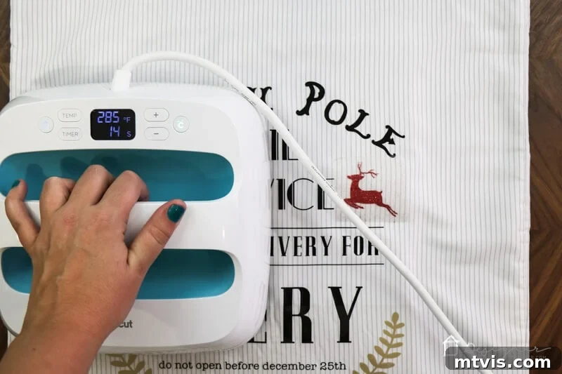 Handcrafted Santa Sacks for Magical Christmas Mornings 6 Close-up photo showing the final steps of ironing on personalized elements like a child's name and reindeer onto a DIY Santa sack