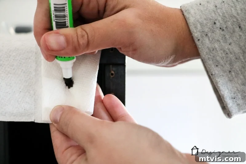 Seamlessly Repair Furniture to Match IKEA Hues 5 A close-up of a woman's hands pressing the tip of a Mohawk 3-in-1 Stick into a paper towel. Paint sticks can be used for easy IKEA furniture repair.
