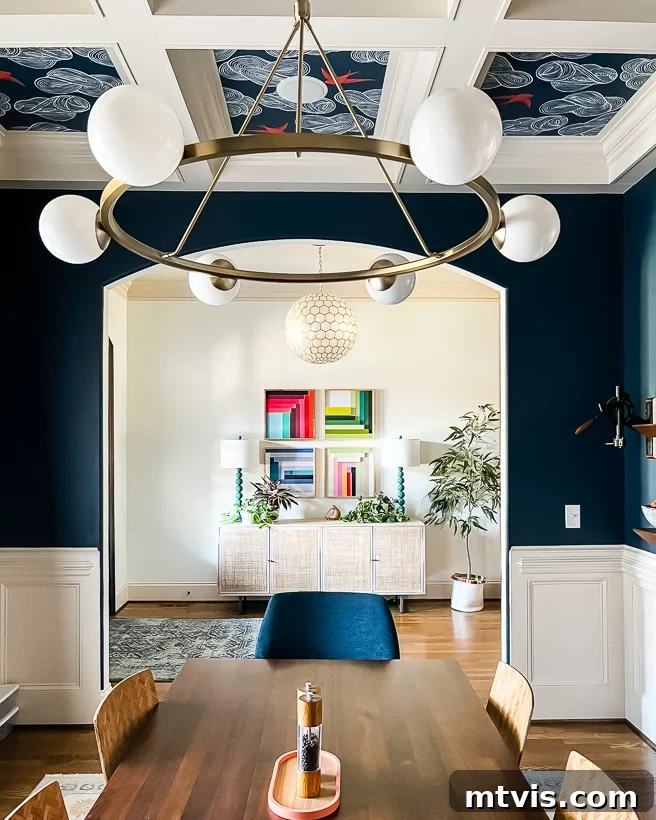 Space-Saving Secrets: 9 Genius Hacks for Bigger-Looking Rooms 11 A dining room with deep blue walls, white shiplap, and a dining table. An arch into the hallways shows artwork and a credenza. This 'after' shows how lighter colors in adjacent spaces can open up the view.