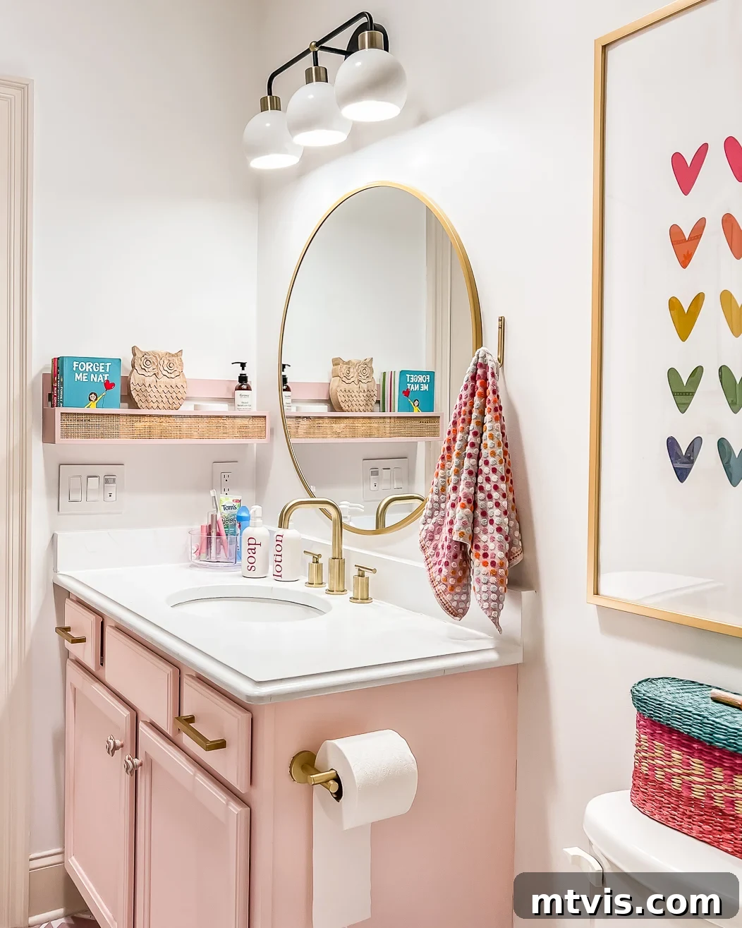 Space-Saving Secrets: 9 Genius Hacks for Bigger-Looking Rooms 18 A round mirror reflects the decorative touches in a cheerful pink and white bathroom. The mirror not only serves a functional purpose but also significantly enhances the perceived size and brightness of the small bathroom.