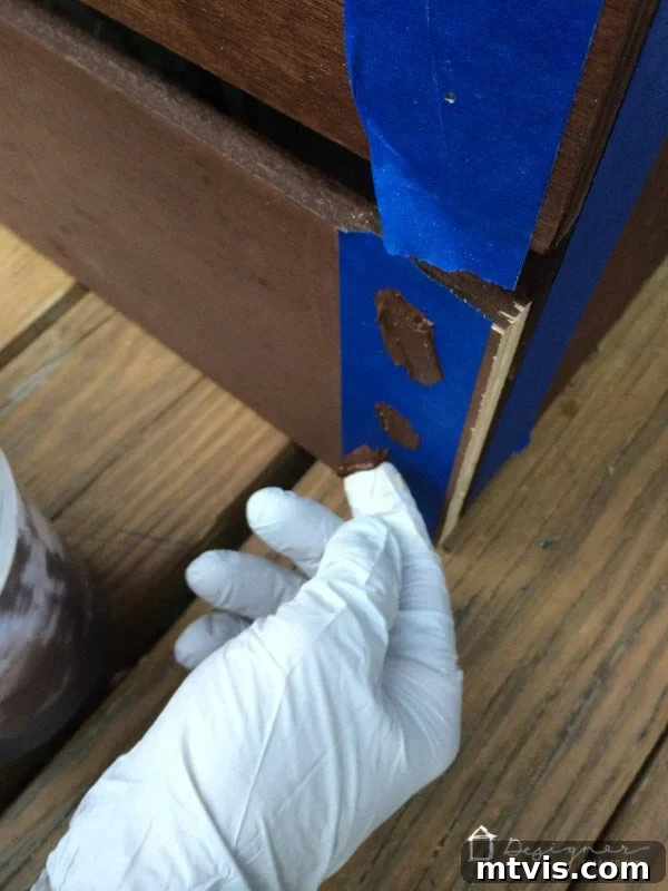 The Art of Invisible Hole Repair 7 Removing painter's tape after filling a pre-stained nail hole, revealing a seamless repair