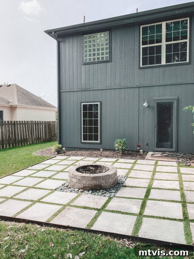 From Cozy Corners to Grand Gatherings: Fire Pit Ideas for All Spaces 13 This inspiring fire pit idea showcases a modern patio design using pavers with strips of astroturf in between, framing a central fire pit positioned elegantly behind the house, creating a harmonious outdoor living area.