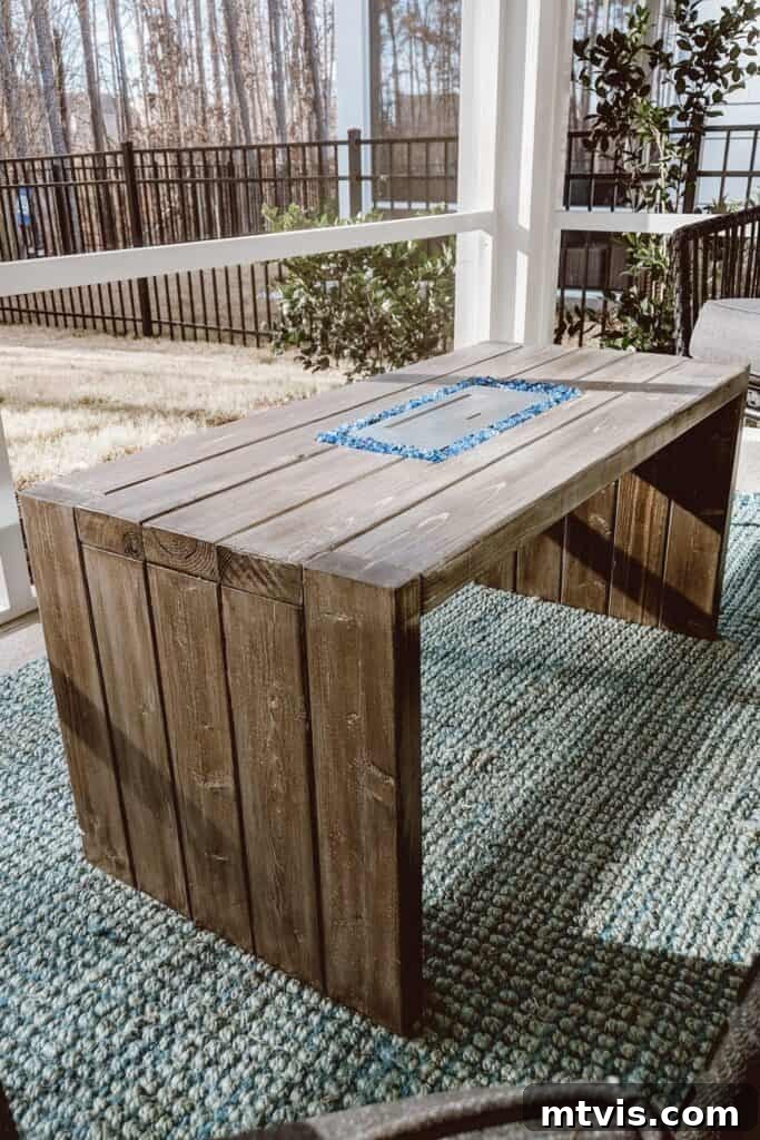 From Cozy Corners to Grand Gatherings: Fire Pit Ideas for All Spaces 4 A charming back porch featuring a vibrant green outdoor rug and a minimalist planked coffee table with a discreet, built-in miniature fire pit, perfect for small gatherings.