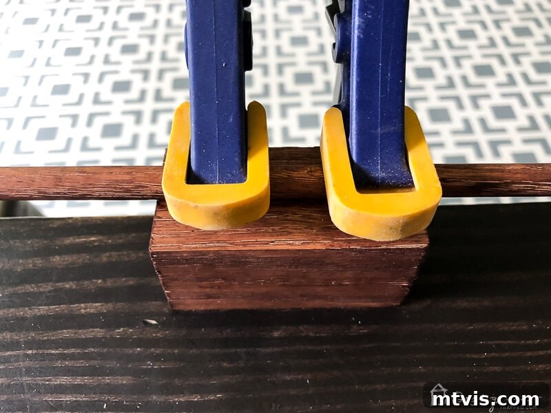 Sparkle and Store: DIY Jewelry Organizers for Every Piece 11 Wood clamps securing a dowel to a block while glue sets