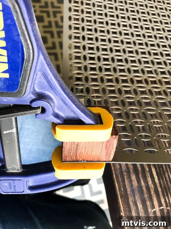 Sparkle and Store: DIY Jewelry Organizers for Every Piece 8 Close-up of a clamped wood block on the corner of the aluminum sheet