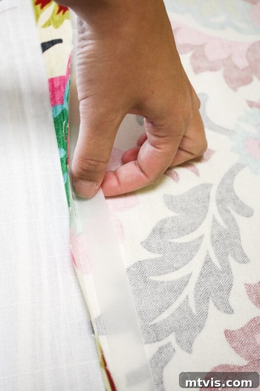 Effortless No-Sew Curtain Hack 6 Applying iron-on hem tape to the folded edge of fabric.