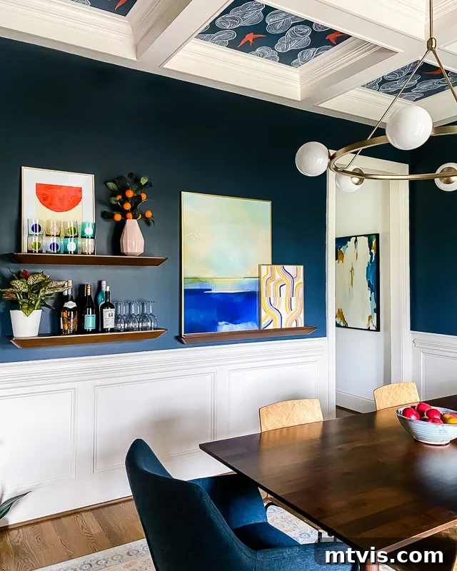 Beyond Beige: Your Starter Guide to Decorating with Color 13 Navy blue dining room wall with an art ledge and shelves displaying colorful barware and a light pink vase with orange blossoms.