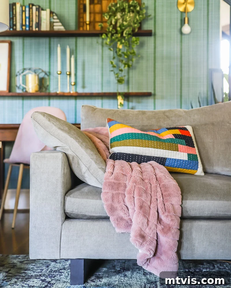 Beyond Beige: Your Starter Guide to Decorating with Color 8 West Elm Harmony sofa with colorful throw pillows positioned against a white wall with a section of patterned wallpaper on the adjacent staircase wall.